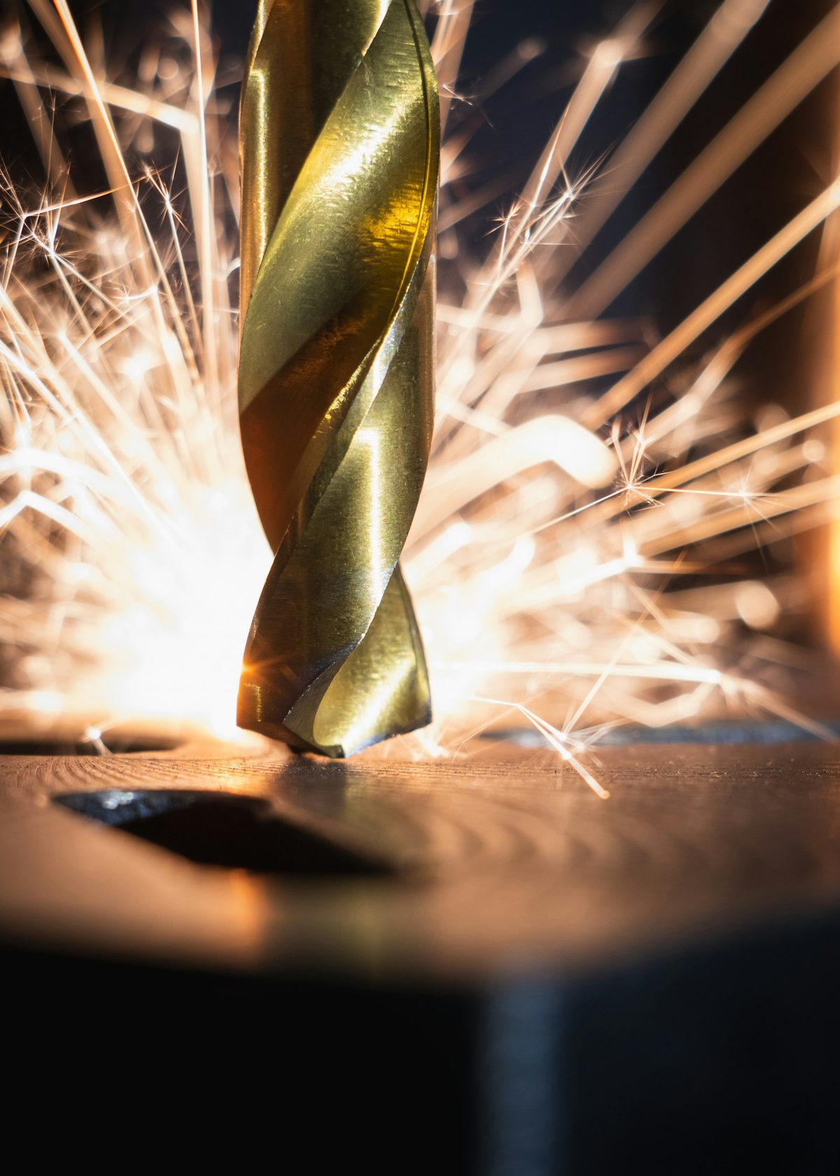 A drill bit throwing sparks as it cuts metal